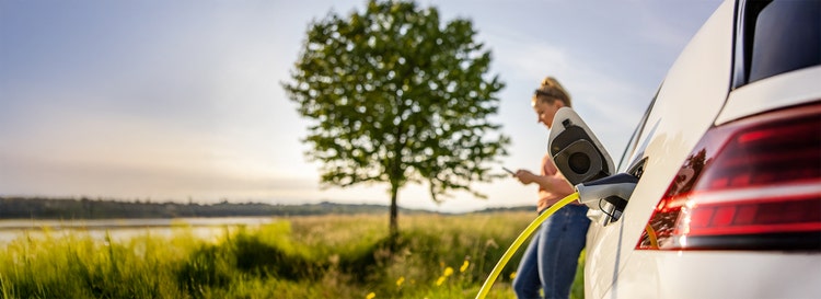 A woman charging her EV on the countryside. Contact Maxxia for EV novated lease.