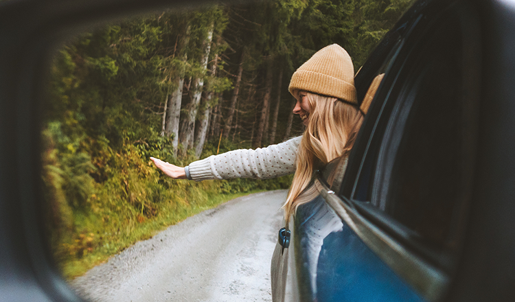 A happy girl waving from her car. Learn how you could save on tax, get a great deal, manage your budget with a novated lease.