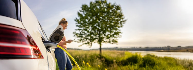 A woman charging her EV on the countryside. Contact Maxxia for EV novated lease.