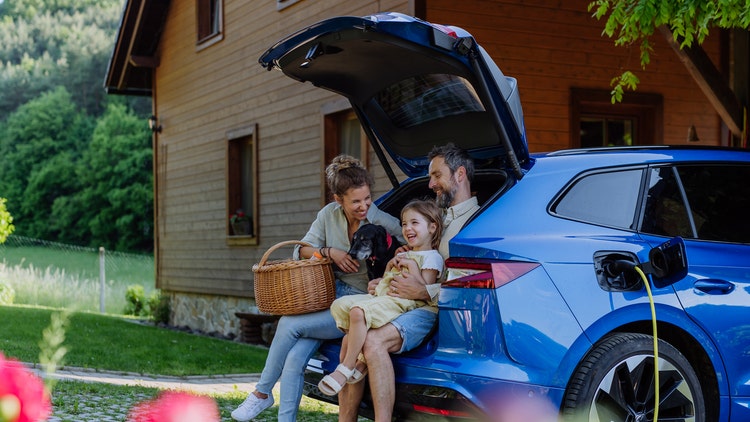 A family sitting on their car boots smiling. How to get a great new car deal and enjoy the advantages of novated leasing.