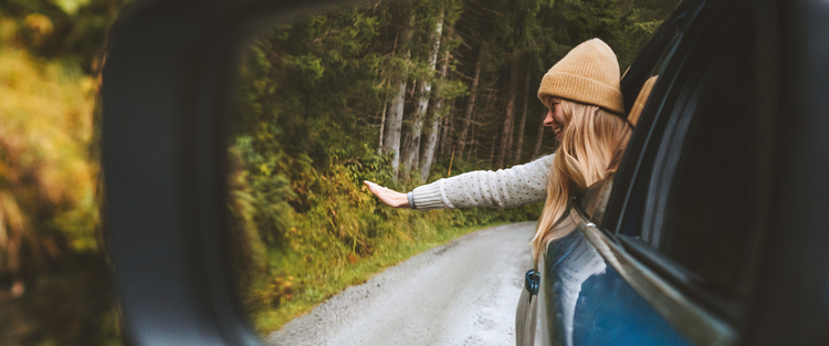 A happy girl waving from her car. Learn how you could save on tax, get a great deal, manage your budget with a novated lease.