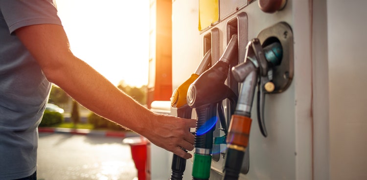 A man holding a fuel nozzle at a service station in Australia