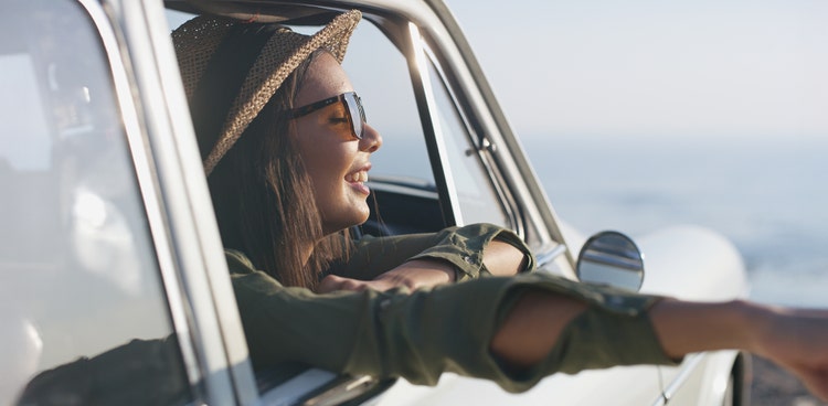 A girl reaching out of her new car window smiling after taking on a novated lease through Maxxia.
