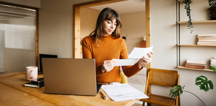 A woman smiling looking paperwork for salary packaging