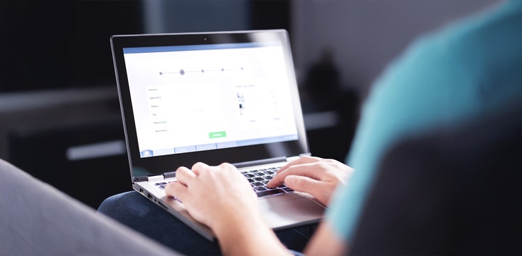 An employee typing on her laptop that is sitting on her lap ready to claim her FBT free salary packaging benefits through Maxxia.