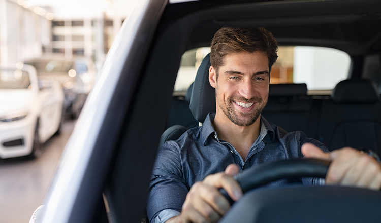 A man smiling while driving his car. Learn how you could get the usual tax benefits of novated leasing a second-hand vehicle.