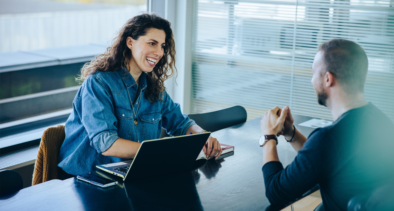 A woman having an interesting discussion with a man in the office.