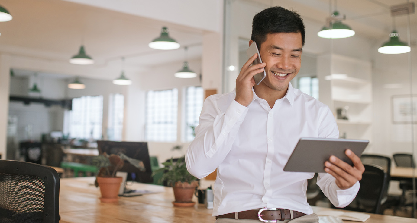 A man on a phone smiling in the office.