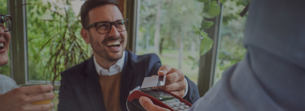 A man tapping maxxia wallet card on eftpos machine for meal entertainment.