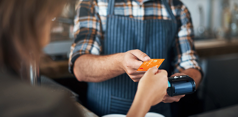 A woman using Maxxia Card on Eftpos machine for meals and entertainment.