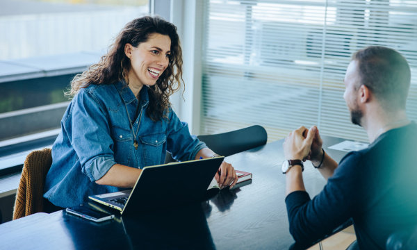 A woman having an interesting discussion with a man in the office.