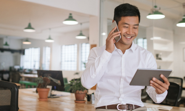 A man on a phone smiling in the office.