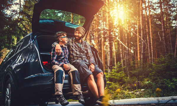 Father and son sitting in car boot.