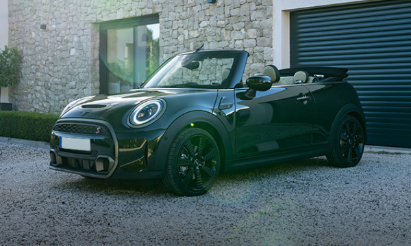 New Mini Cooper convertible parked in front of a garage.