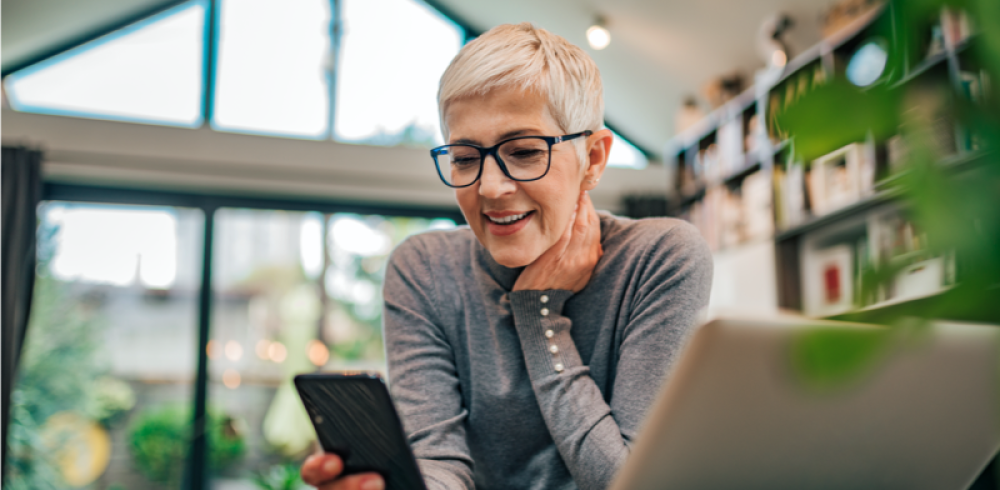 Portrait of a cheerful senior businesswoman using smart phone at home office, close-up