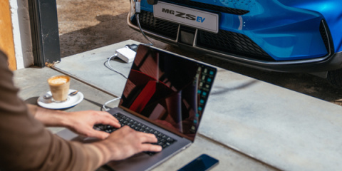User using their laptop charged to an EV.