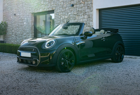 New Mini Cooper convertible parked in front of a garage.
